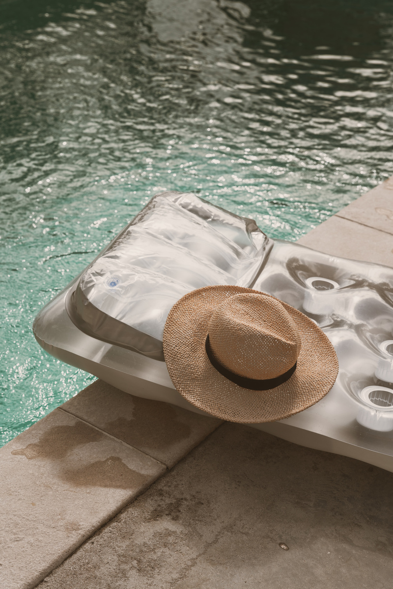 Pool Lifestyle Inflatable Mattress and Hat by a Pool
